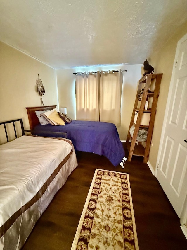 bedroom with baseboards, a textured ceiling, and wood finished floors