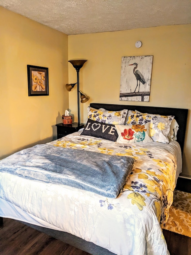 bedroom with a textured ceiling and wood finished floors