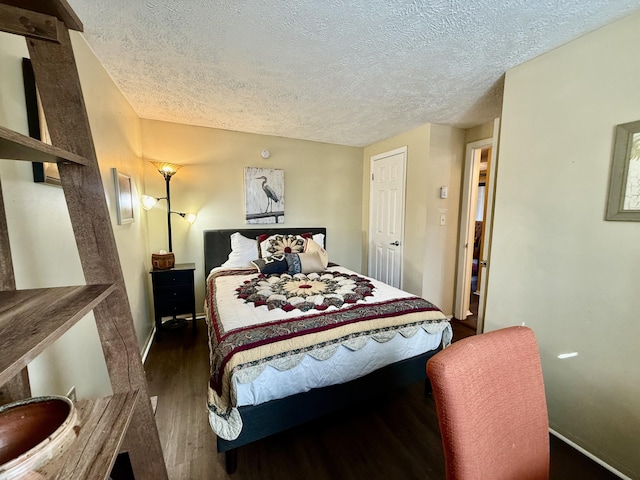 bedroom with a textured ceiling, baseboards, and wood finished floors