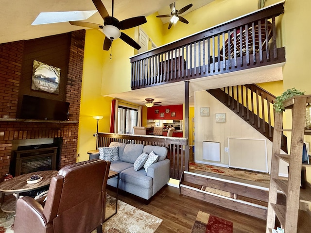 living room with high vaulted ceiling, stairs, a fireplace, ceiling fan, and wood finished floors