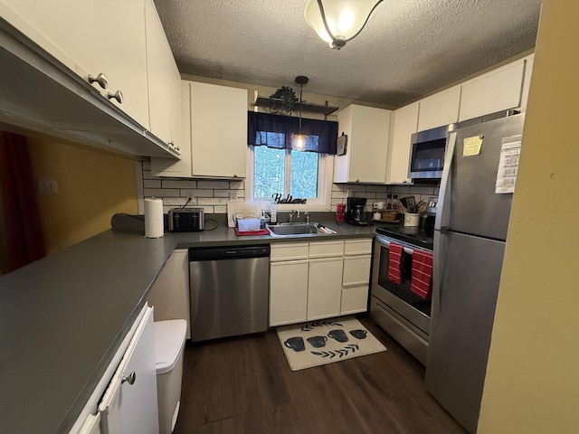 kitchen featuring white cabinetry, a sink, appliances with stainless steel finishes, and dark wood finished floors