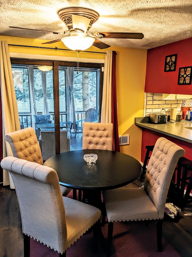 dining room with a textured ceiling, visible vents, ceiling fan, and wood finished floors