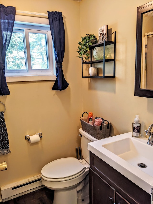 half bathroom featuring toilet, vanity, and a baseboard radiator