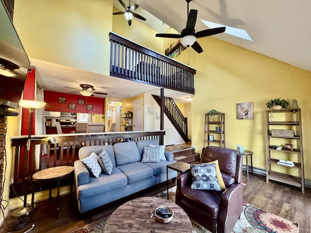 living area featuring a ceiling fan, baseboards, stairway, and wood finished floors