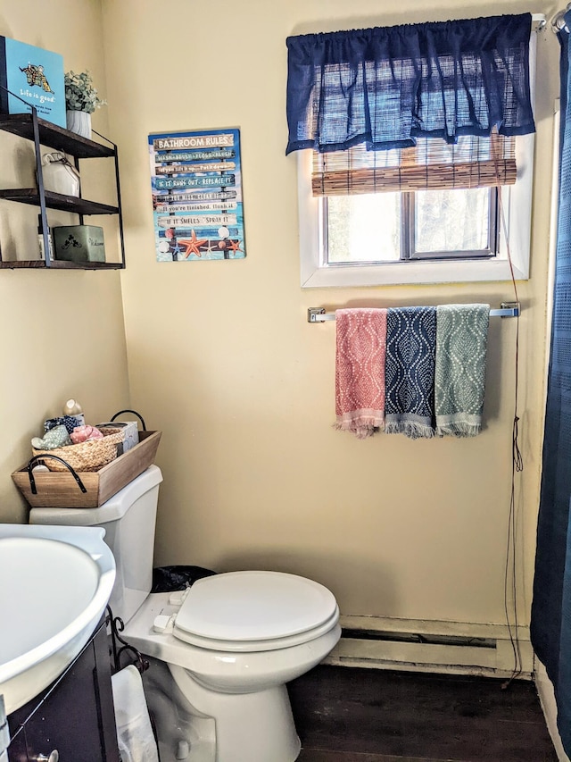 bathroom with a baseboard radiator, wood finished floors, toilet, and vanity