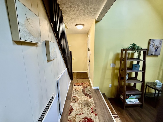 hallway featuring baseboards, visible vents, wood finished floors, and a textured ceiling