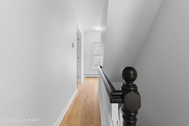 hall featuring light wood-type flooring, baseboards, baseboard heating, and an upstairs landing