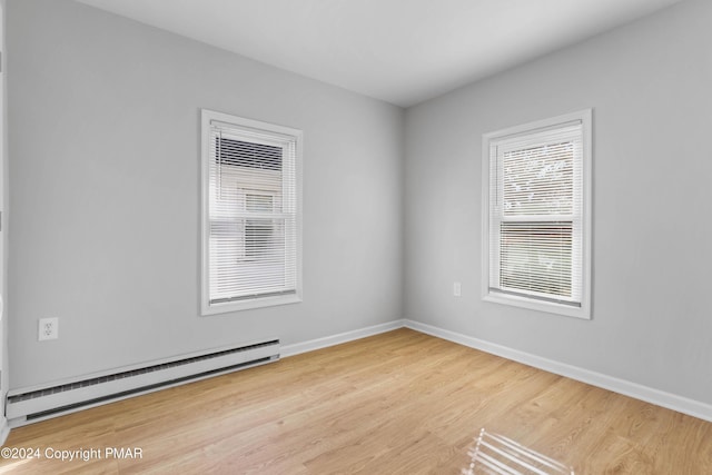 spare room with a baseboard radiator, wood finished floors, and baseboards