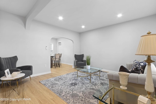 living room featuring arched walkways, baseboards, wood finished floors, and recessed lighting