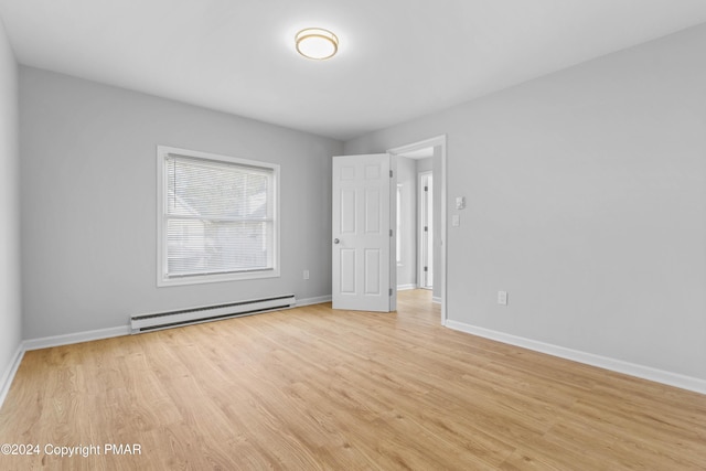 spare room with baseboards, light wood finished floors, and baseboard heating