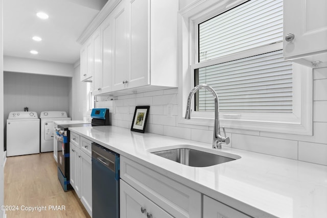 kitchen with white cabinets, a sink, stainless steel range with electric stovetop, washer and dryer, and dishwashing machine