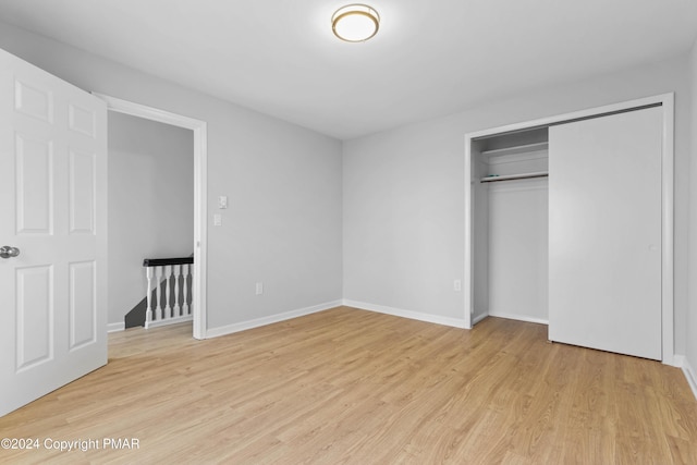 unfurnished bedroom with light wood finished floors, a closet, and baseboards