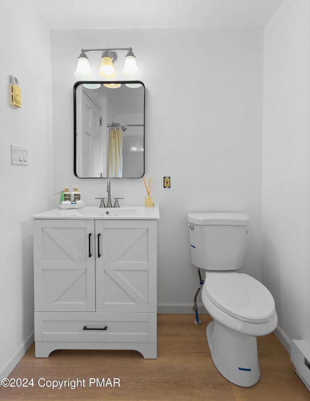 bathroom with baseboards, vanity, toilet, and wood finished floors