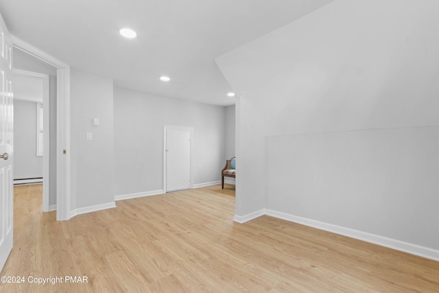 unfurnished room with light wood finished floors, a baseboard radiator, recessed lighting, and baseboards