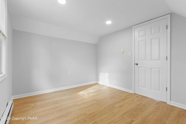 additional living space featuring a baseboard heating unit, light wood-type flooring, and baseboards