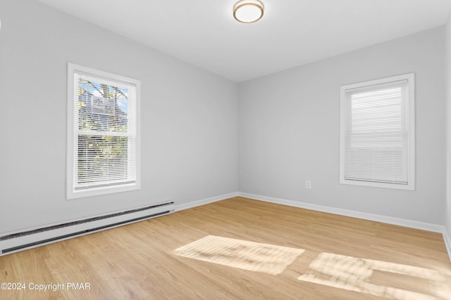 spare room featuring baseboards, a baseboard heating unit, and wood finished floors