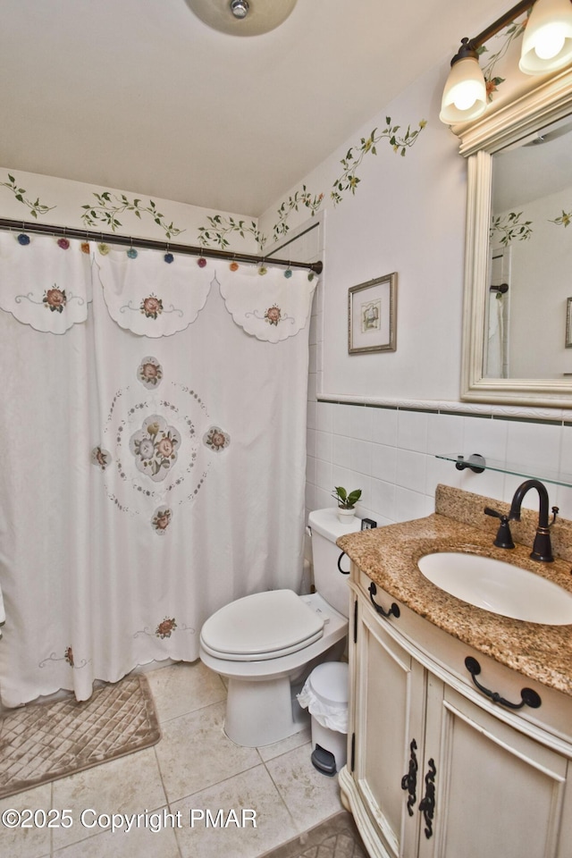 bathroom featuring toilet, a shower with curtain, tile patterned floors, vanity, and tile walls