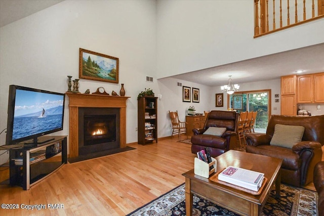 277 Packanack Dr, Clifton Township, PA 18424 - living room featuring light wood-style floors, a chandelier, a fireplace with flush hearth, and a towering ceiling