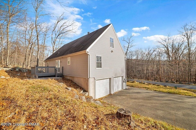 120 St Andrews Dr, Bushkill, PA 18324 - view of side of home featuring a deck, a garage, and asphalt driveway