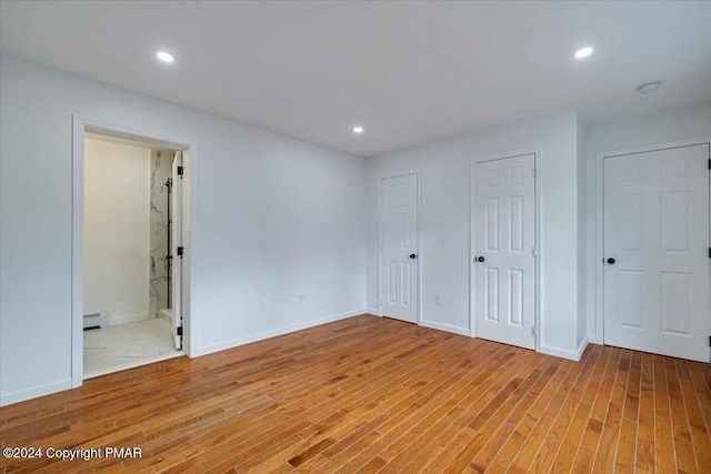 120 St Andrews Dr, Bushkill, PA 18324 - unfurnished bedroom featuring baseboard heating, light wood-style flooring, two closets, recessed lighting, and baseboards