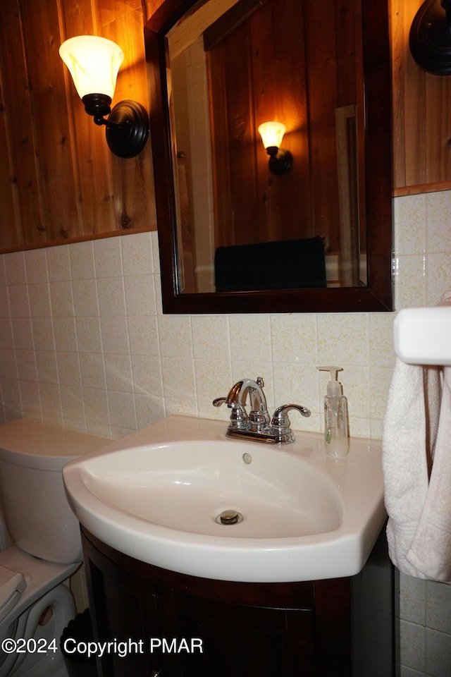 half bath featuring toilet, tile walls, and vanity