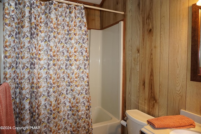 bathroom featuring shower / bath combo, wooden walls, and toilet