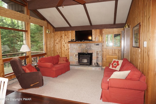 living area with vaulted ceiling with beams, a wood stove, wood walls, and wood finished floors