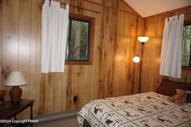 bedroom featuring vaulted ceiling, wood walls, and multiple windows