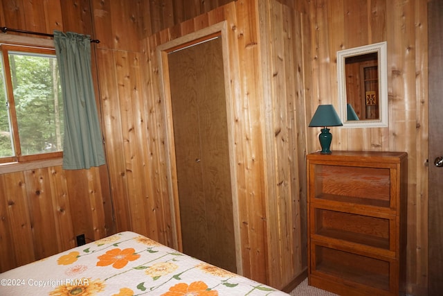 bedroom featuring multiple windows and wooden walls