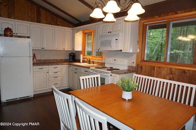 kitchen featuring white appliances, a sink, white cabinets, vaulted ceiling, and decorative backsplash