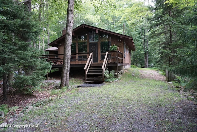 view of front of house featuring stairs, a forest view, a deck, and a chimney