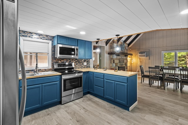 371 Echo Lake Rd, Tobyhanna, PA 18466 - kitchen featuring appliances with stainless steel finishes, blue cabinetry, a peninsula, vaulted ceiling, and wooden walls