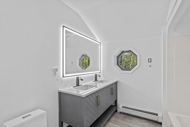 371 Echo Lake Rd, Tobyhanna, PA 18466 - full bathroom with baseboard heating, vaulted ceiling, double vanity, wood finished floors, and a tub