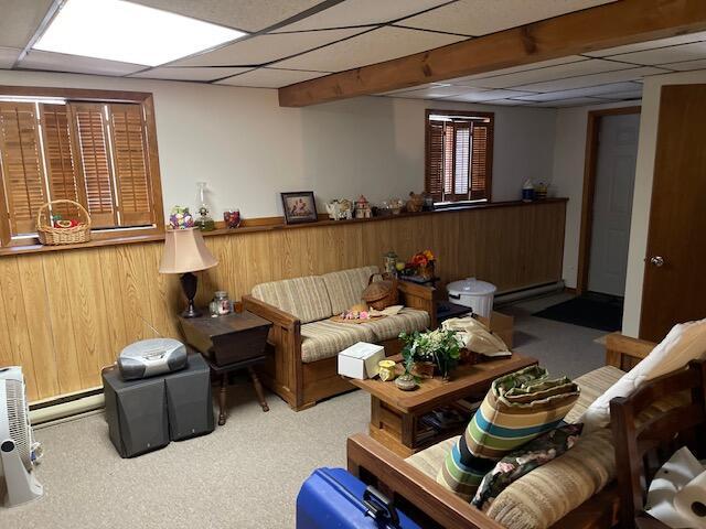 carpeted living room with a drop ceiling, baseboard heating, and a baseboard radiator