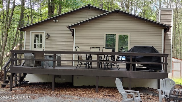 rear view of house with a chimney, stairway, and a wooden deck