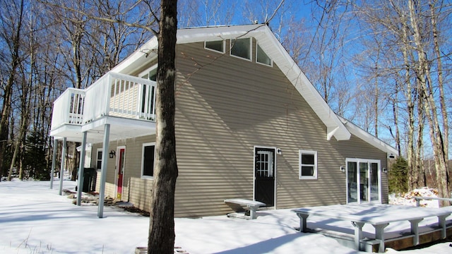 snow covered rear of property featuring a balcony