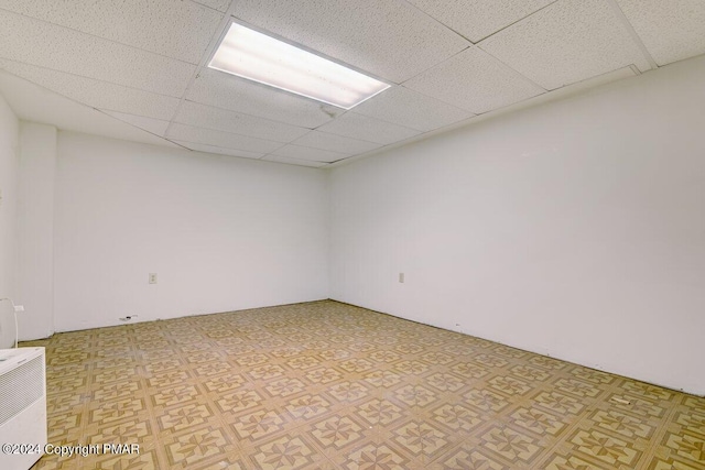 unfurnished room with light floors and a drop ceiling