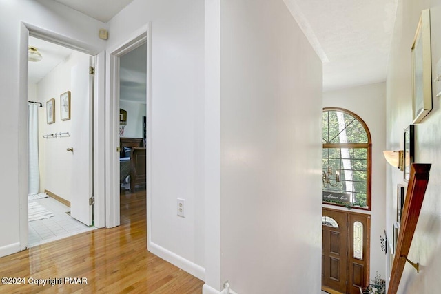 entryway with a fireplace, light wood-style flooring, and baseboards