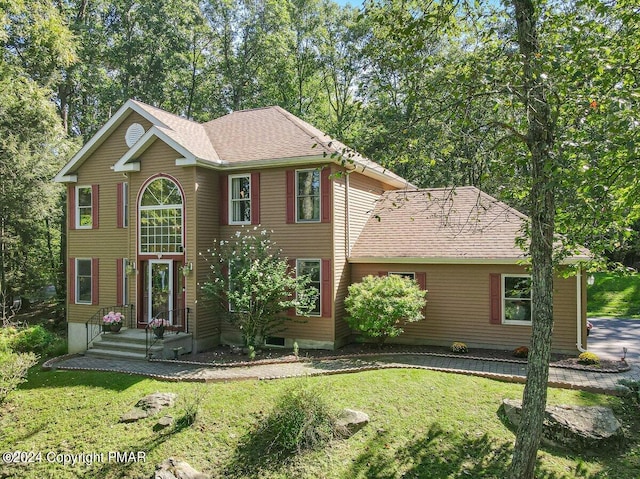 view of front facade with a shingled roof and a front yard