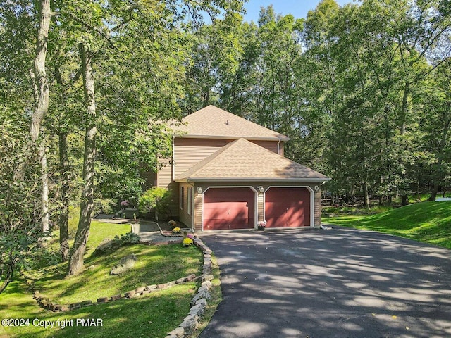 view of side of property with aphalt driveway, an attached garage, a lawn, and a shingled roof