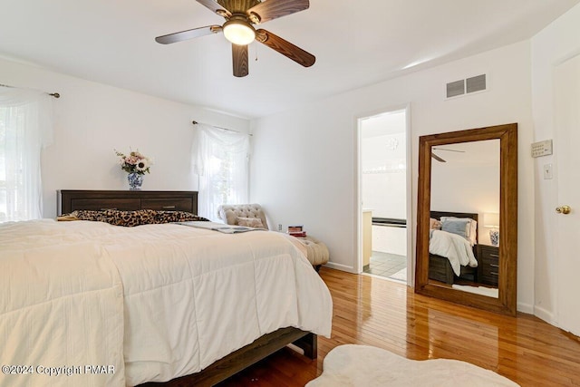 bedroom with visible vents, ensuite bathroom, ceiling fan, wood finished floors, and baseboards