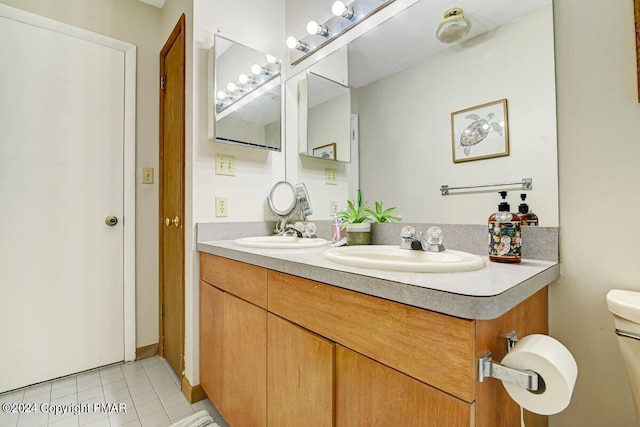 bathroom with tile patterned flooring, a sink, toilet, and double vanity