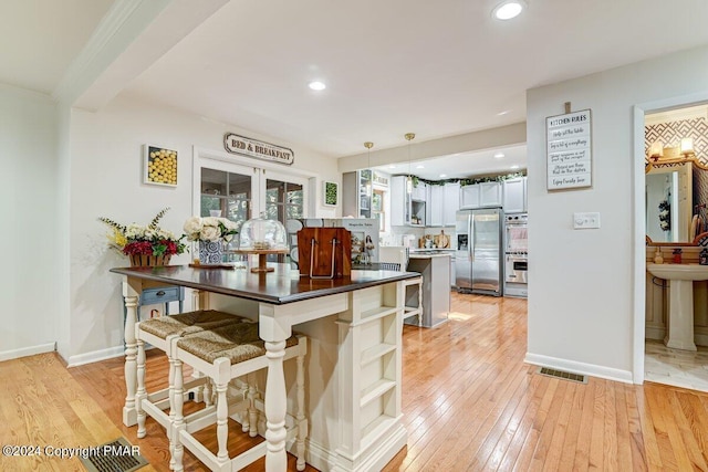 kitchen with visible vents, baseboards, light wood-style floors, open shelves, and stainless steel fridge