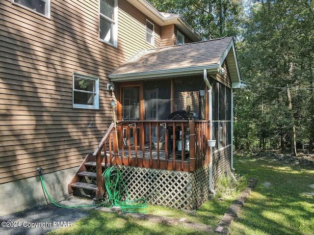 view of exterior entry featuring a deck, a lawn, and roof with shingles