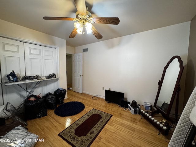 workout room featuring a ceiling fan, baseboards, visible vents, and wood finished floors