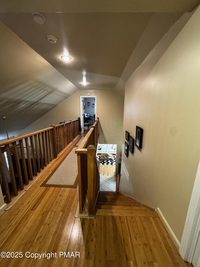 interior space featuring lofted ceiling, baseboards, an upstairs landing, and hardwood / wood-style flooring