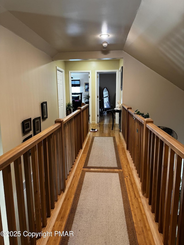 hall featuring light wood-type flooring, an upstairs landing, and lofted ceiling