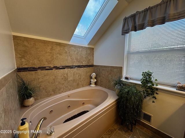 full bathroom featuring a whirlpool tub, vaulted ceiling with skylight, and visible vents