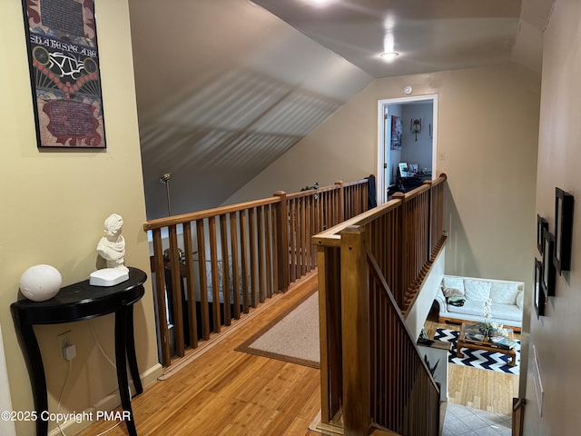 hallway featuring lofted ceiling, an upstairs landing, and wood finished floors