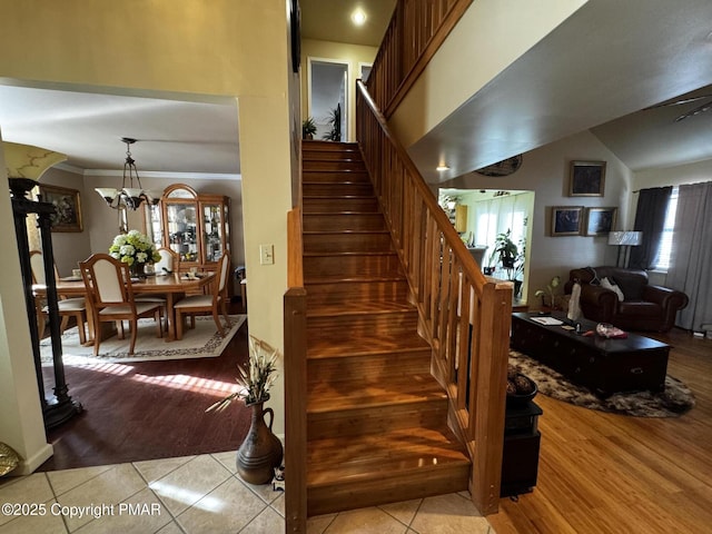 staircase featuring a chandelier, wood finished floors, and crown molding